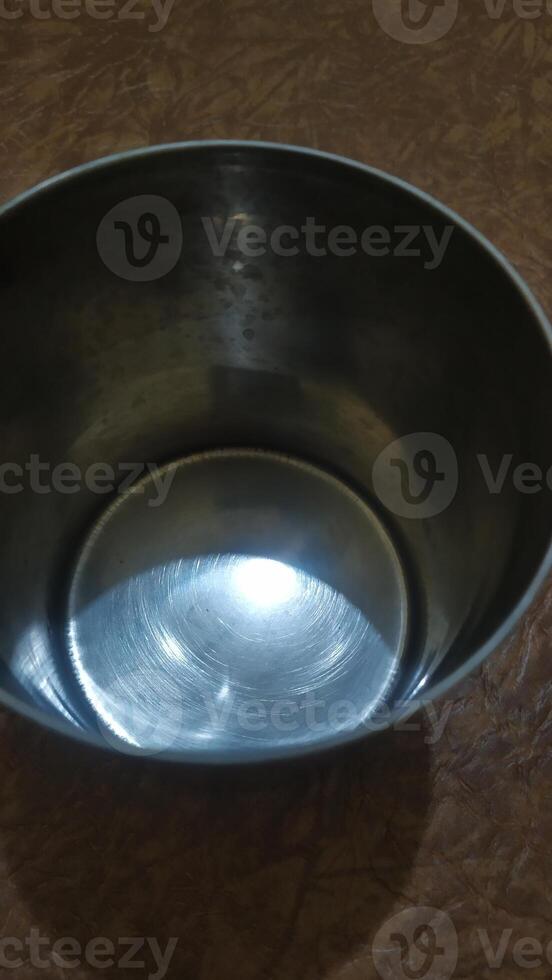 a metal bowl on a table with a light shining in it photo
