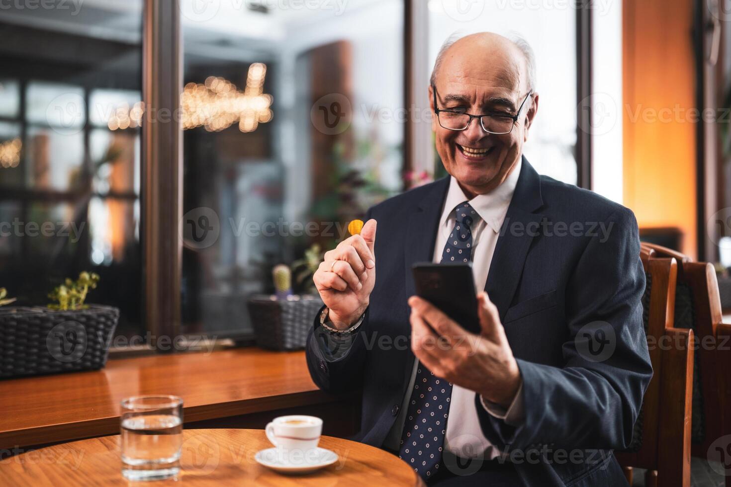 Happy elderly businessman having a call on his mobile phone while relaxing in the bar. photo