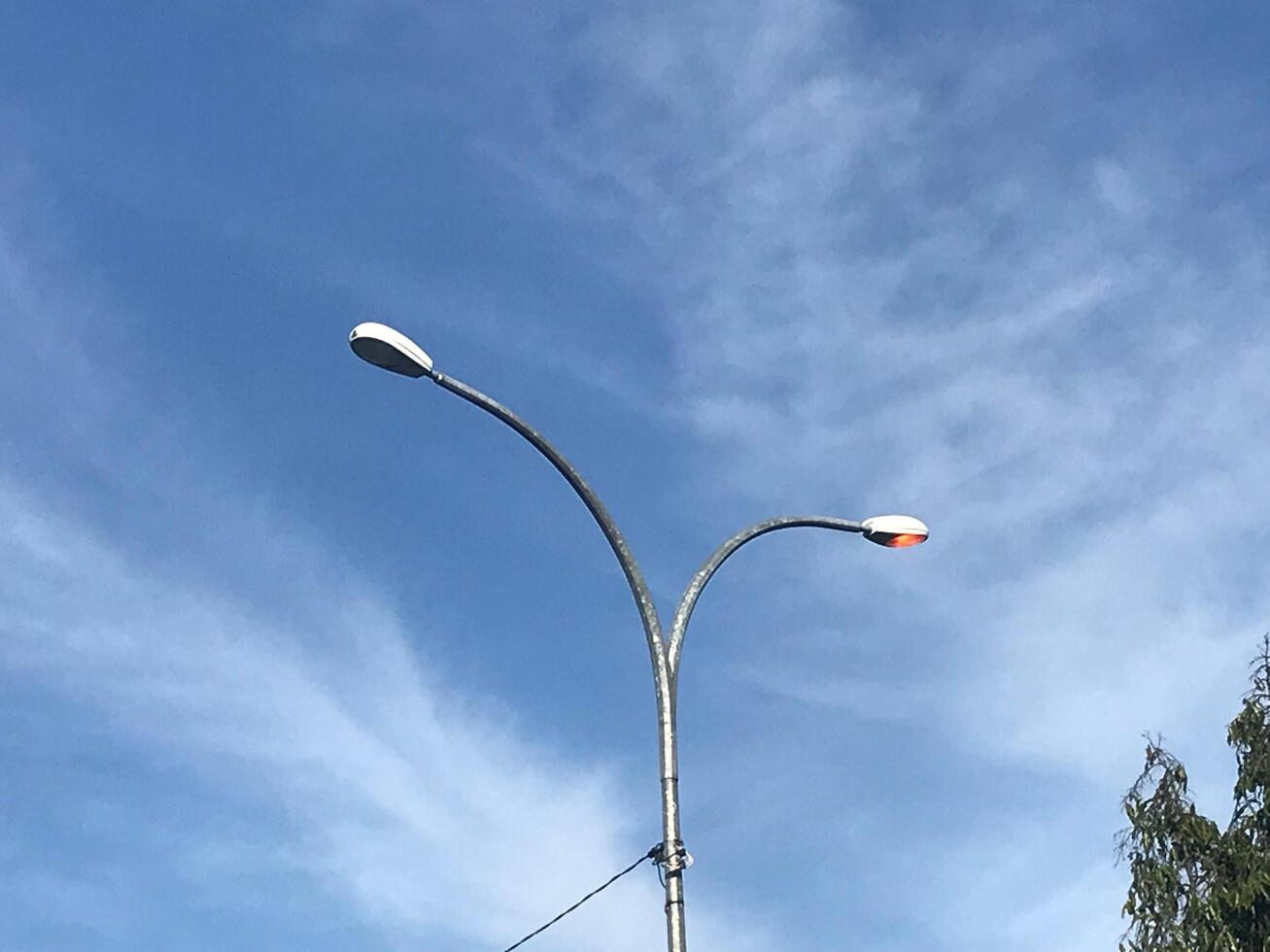 Street light with a red light on top and blue sky photo