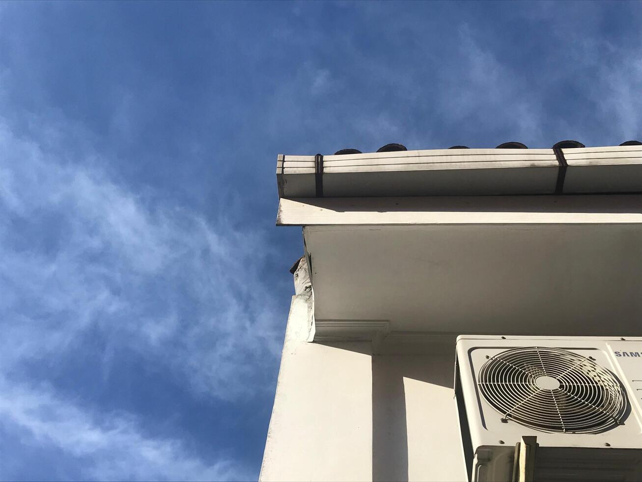 White building with a fan and air conditioner photo