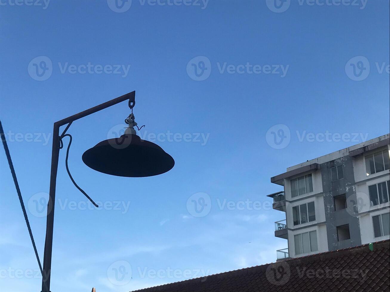 Lamp hanging from a pole in front of a building photo