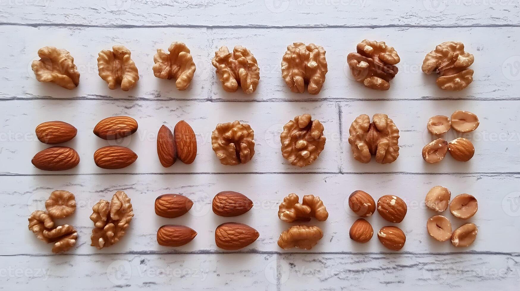 Assorted nuts laid out neatly on a rustic wooden table showcasing walnuts and almonds in creative arrangement photo