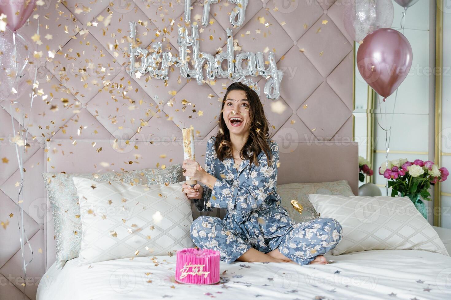 Young Woman Celebrating Birthday with Golden Confetti in Bedroom photo