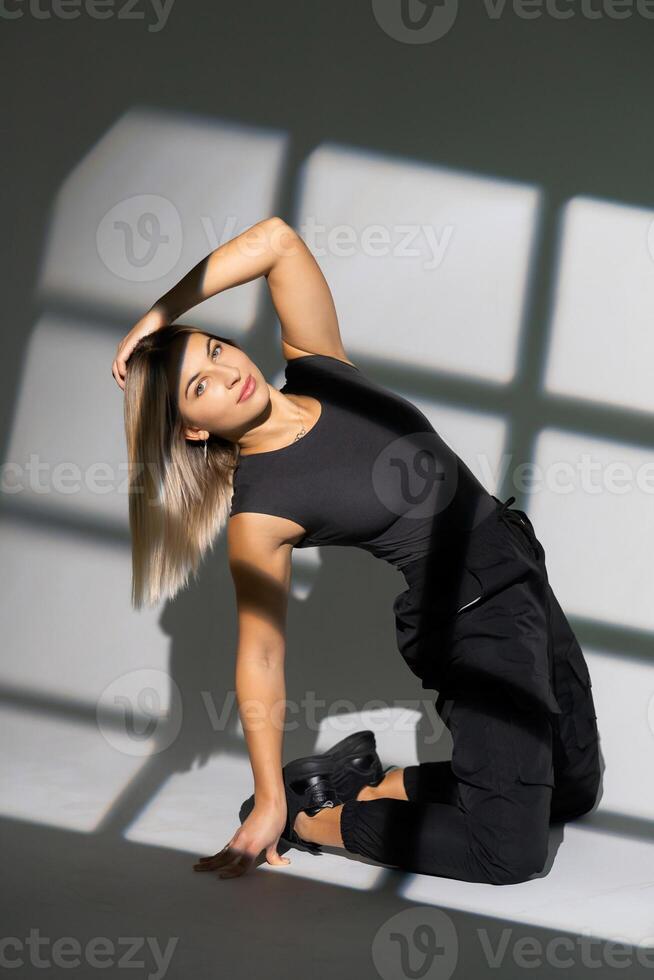 Dancer posing on floor with window shadow projections photo