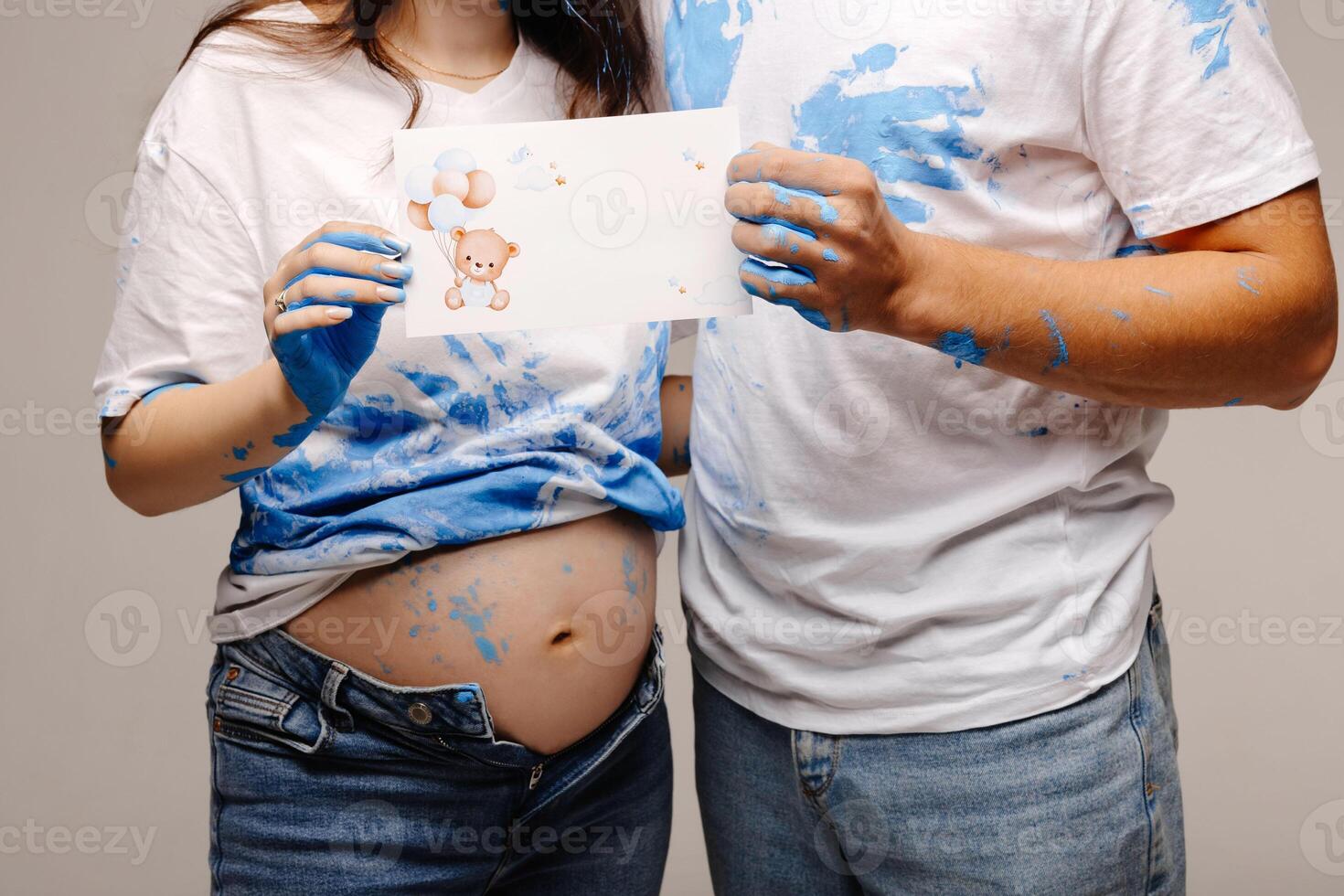 Pregnant couple showing a drawing of a teddy bear with blue balloons photo