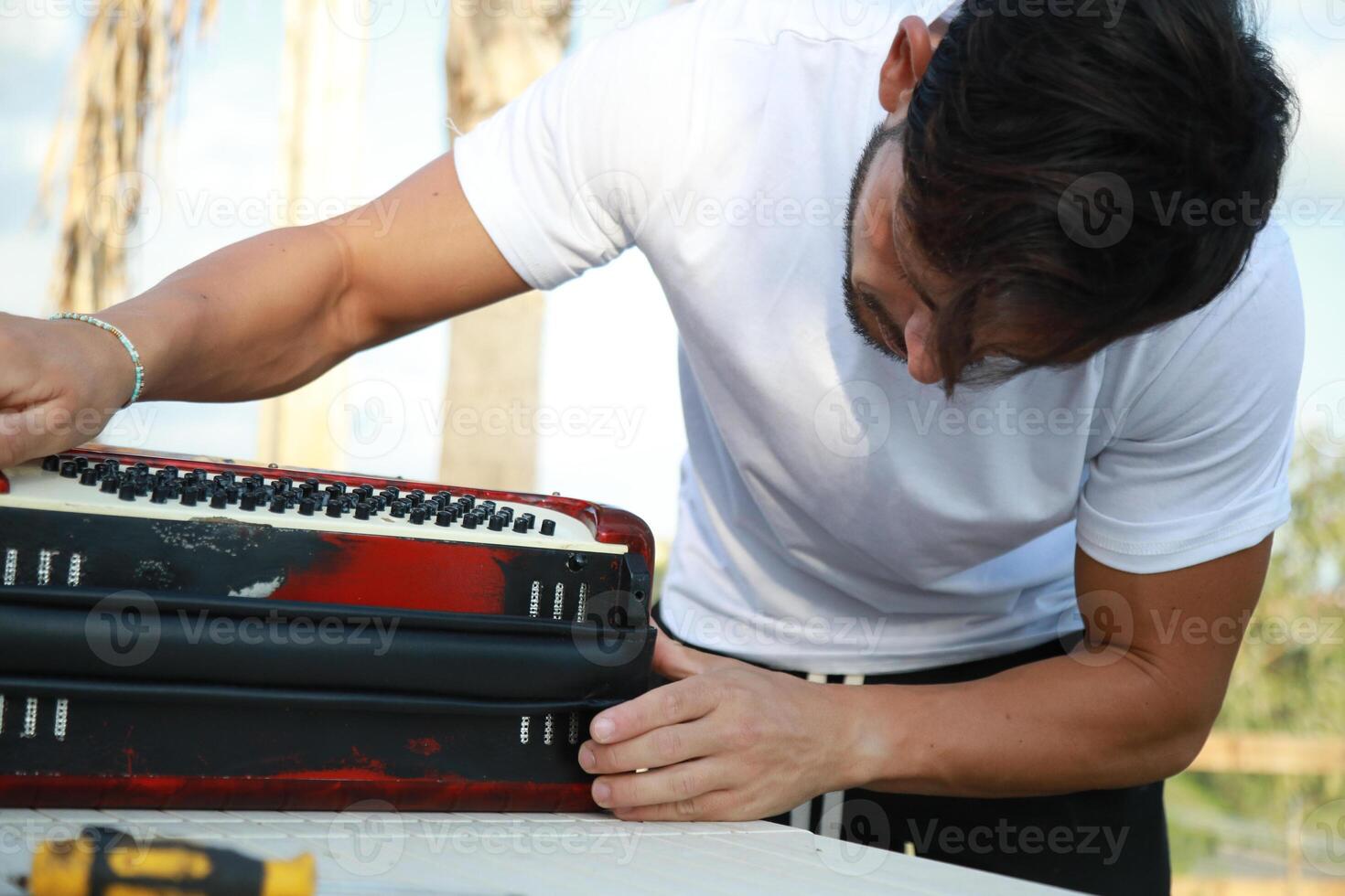 Man Using Tool To Fix And Tune Accordion photo