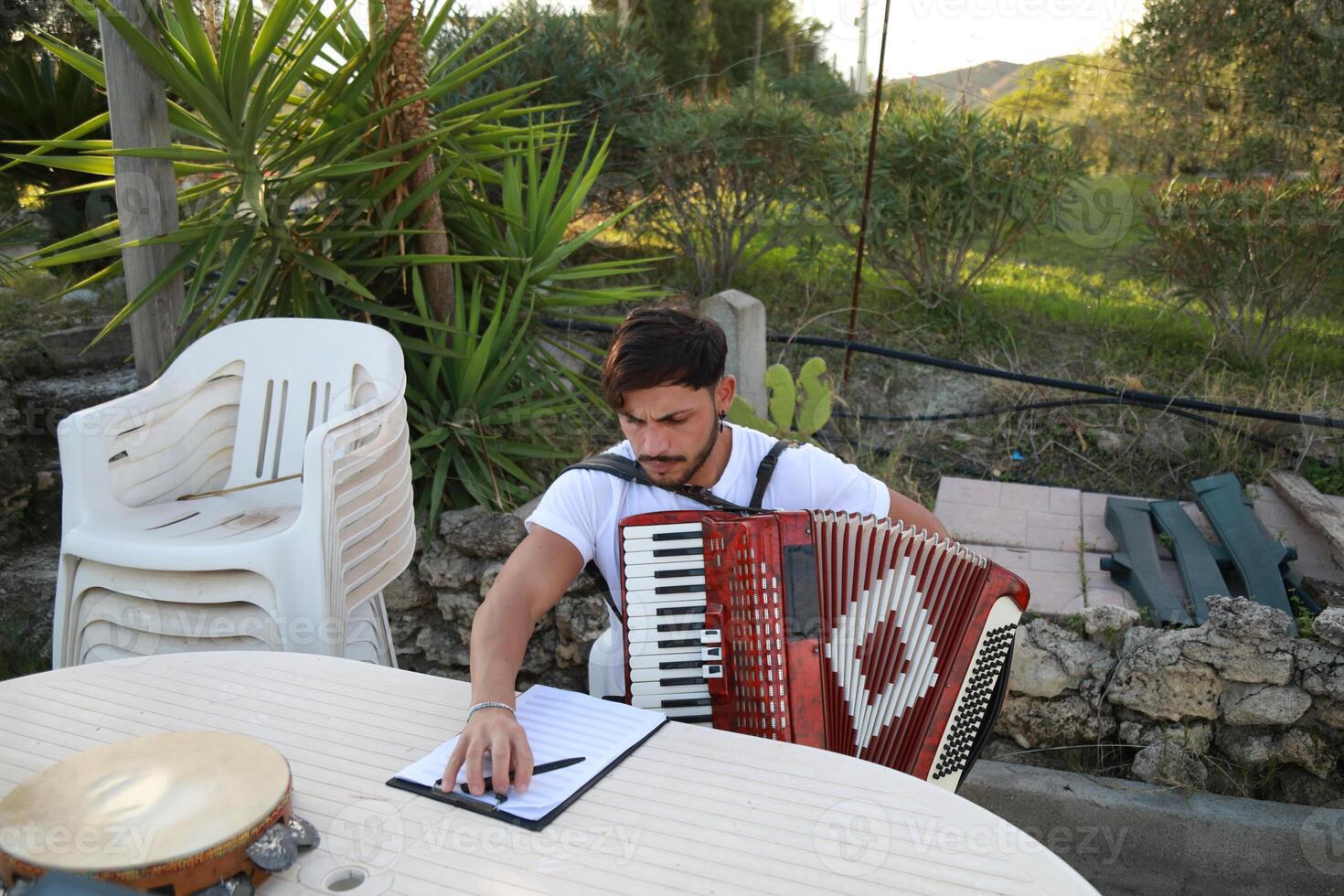 Man Studying Accordion And Watching On The Paper photo