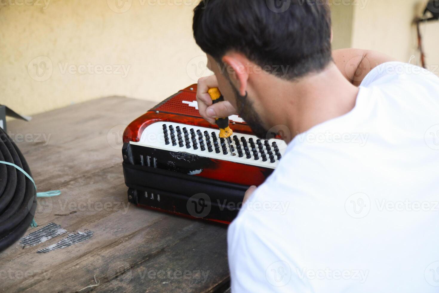 Man Using Tool To Fix And Tune Accordion photo