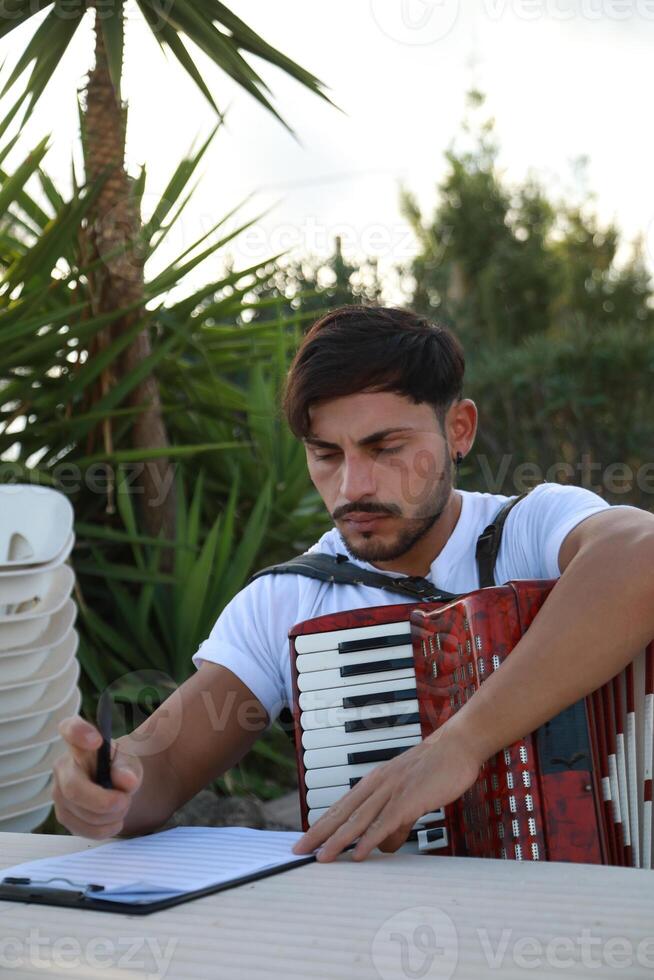 Man Studying Accordion And Watching On The Paper photo