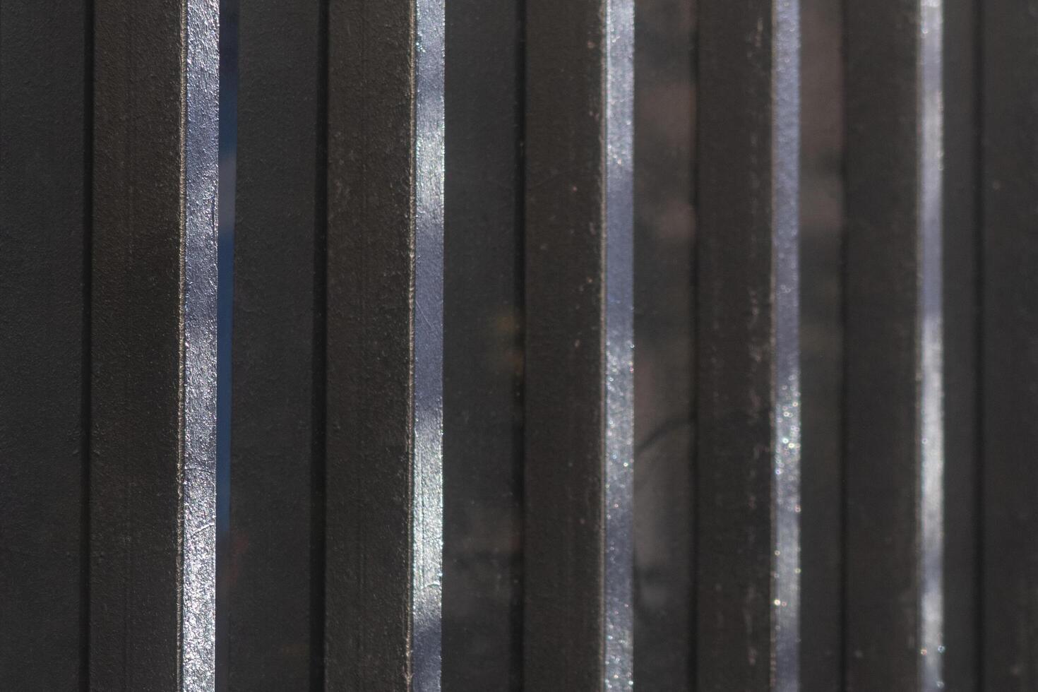 Background or texture. Metallic black fence with vertical light lines. Partically painted. photo