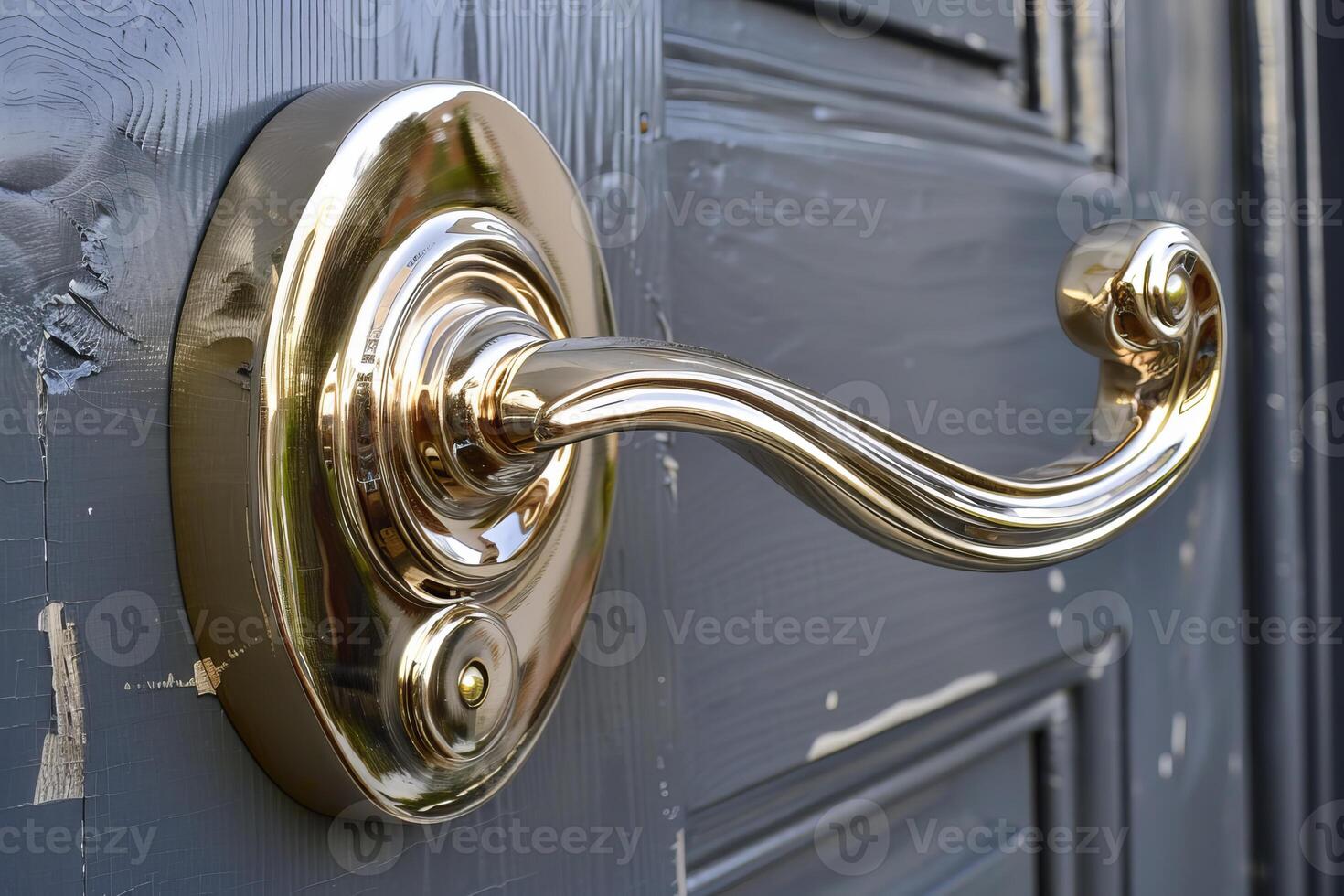 Golden door handle shining on a gray weathered wooden door photo