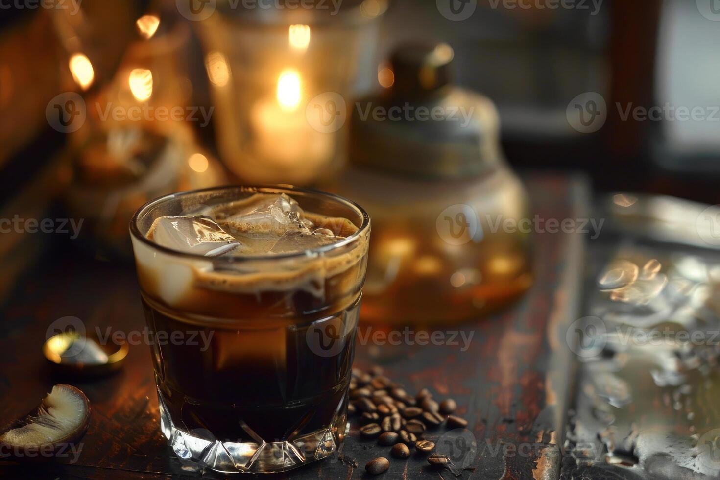 Glass of iced coffee with ice cubes on table with coffee beans and candles in background photo