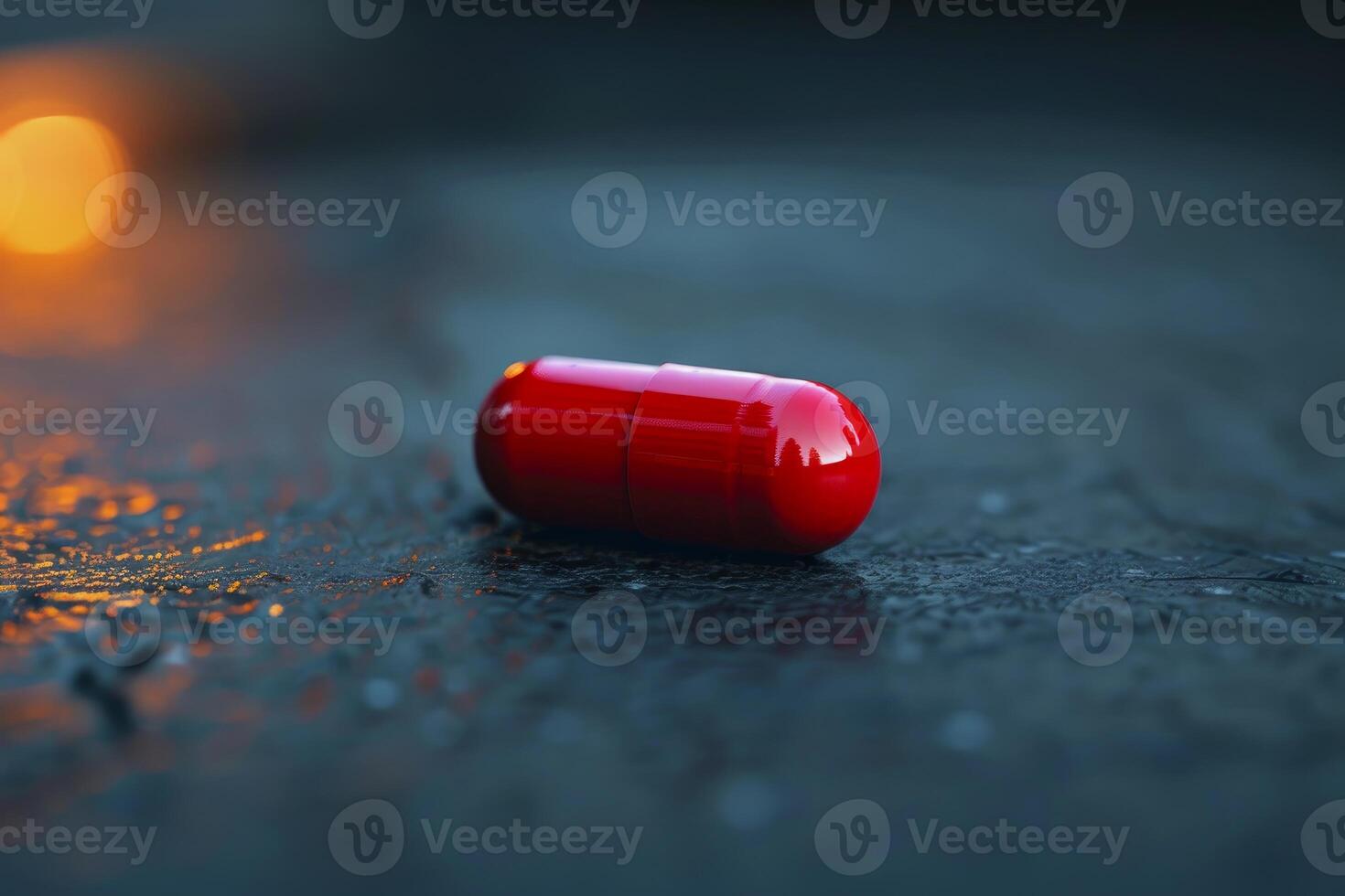 Single red pill lying on dark reflective surface photo
