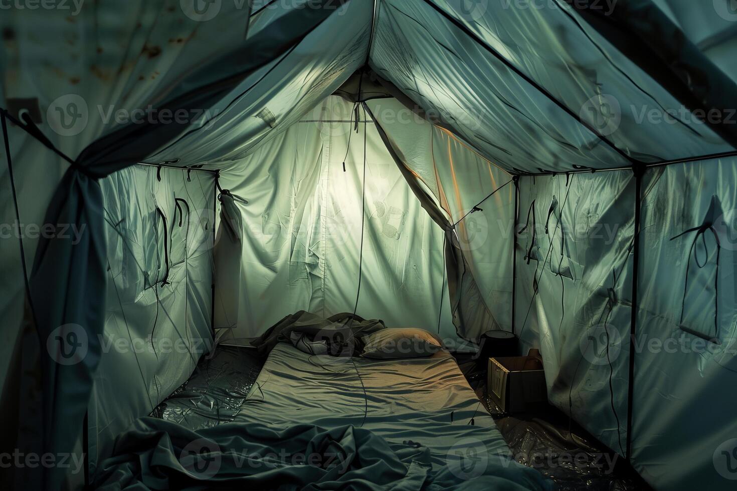 Empty tent illuminated by lamp with bed inside at night photo