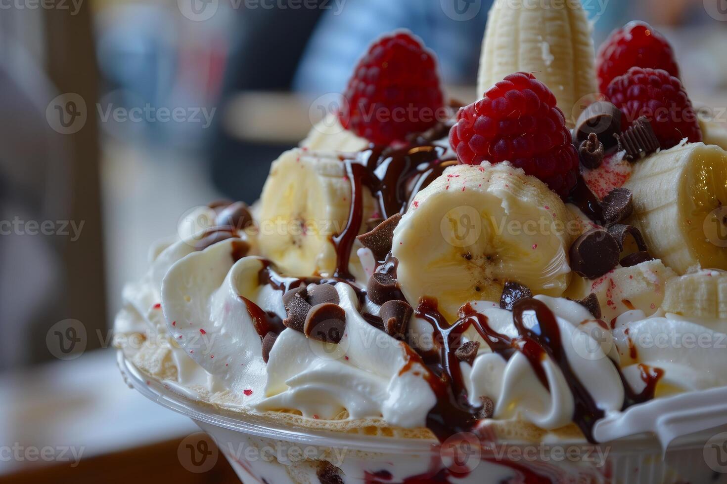 Delicious ice cream dessert with whipped cream, chocolate, banana and raspberry topping photo