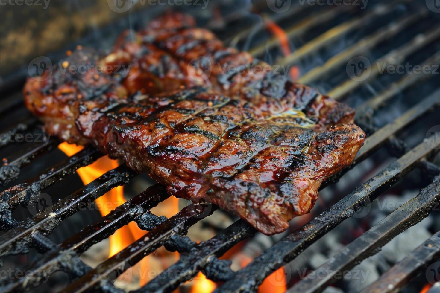 Juicy steak grilling on the barbecue grill over flames photo
