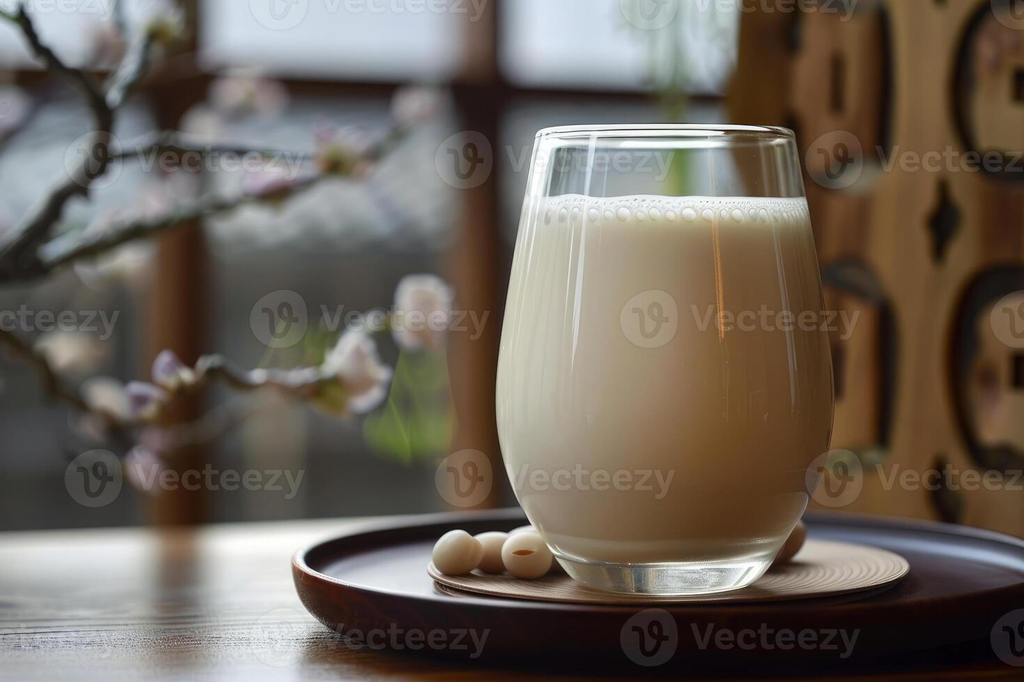 Glass of soy milk with soybeans on a wooden tray resting on a table photo