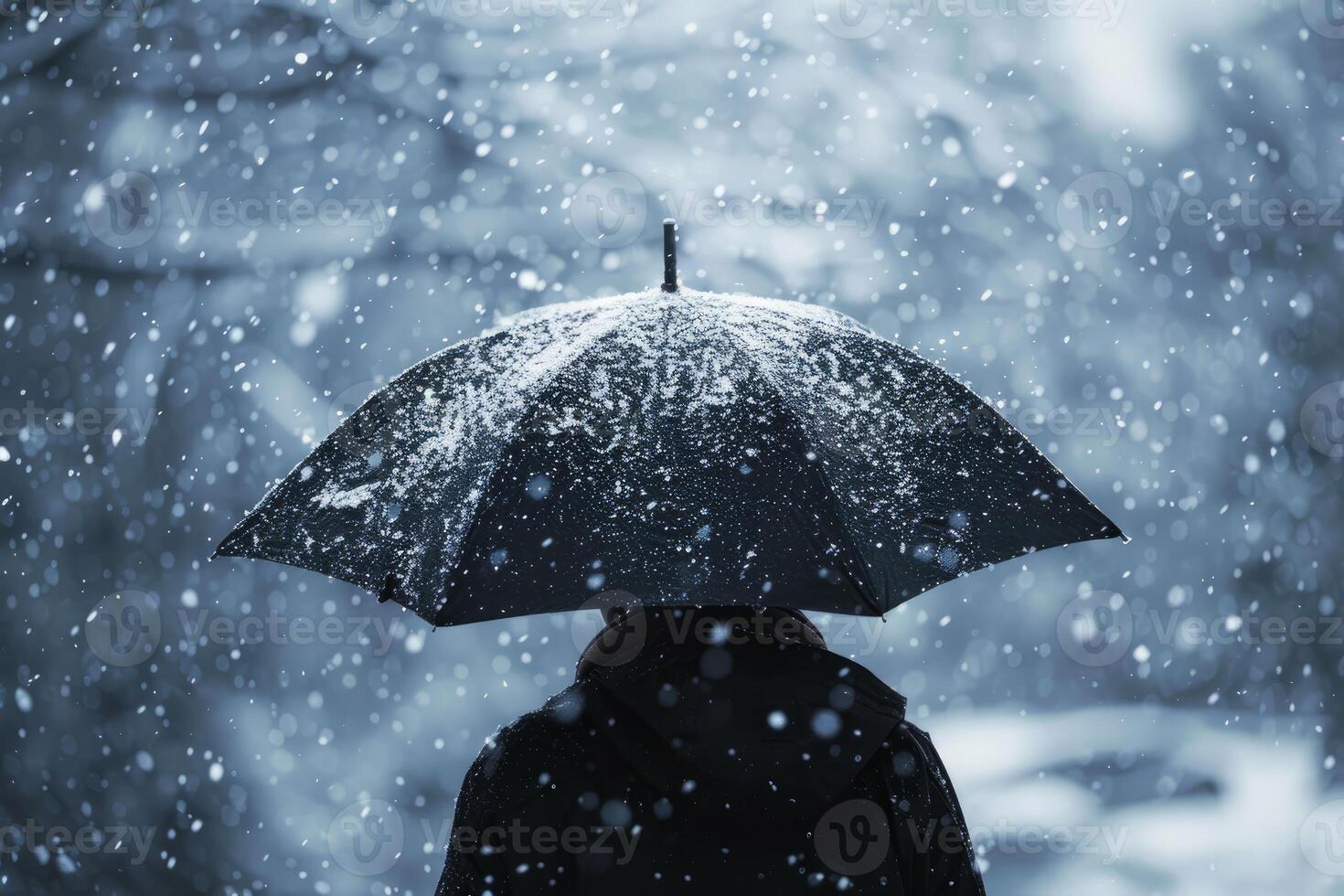 Person holding black umbrella walking in snowing winter day photo