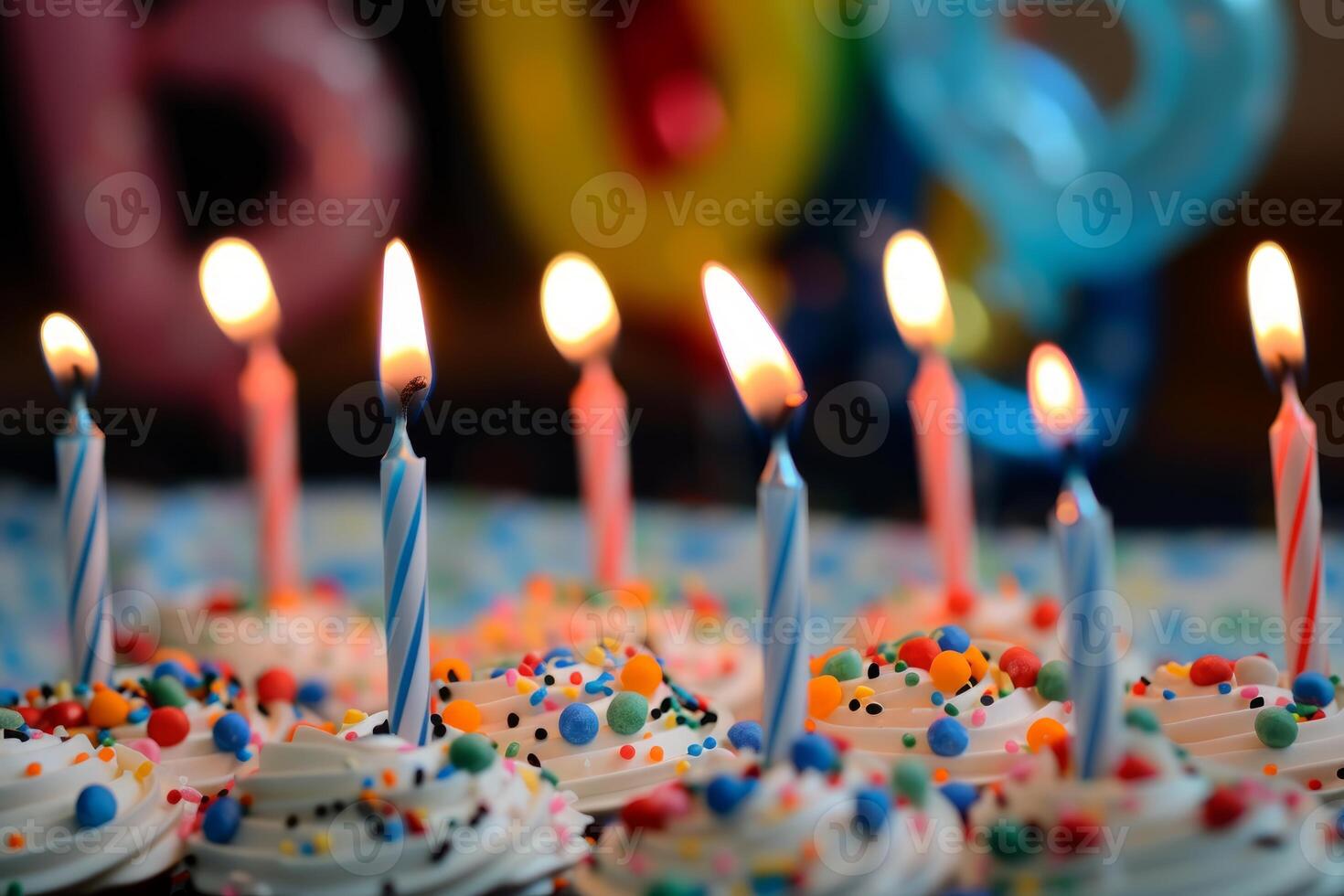Burning birthday candles on colorful sprinkles cupcakes photo