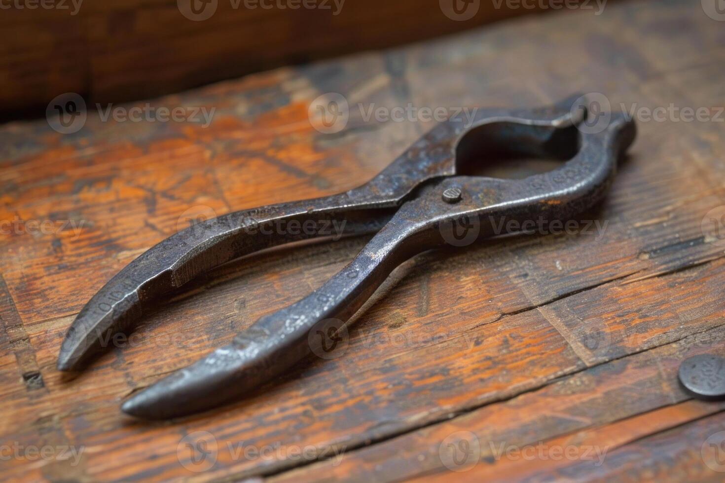 Antique farrier tool laying on wooden surface photo