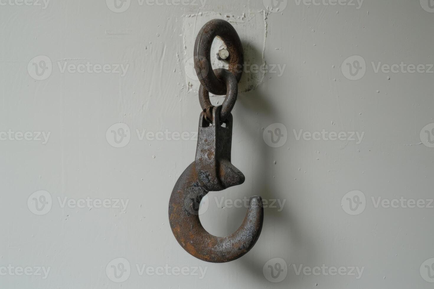 Rusty metal hook hanging on white wall photo
