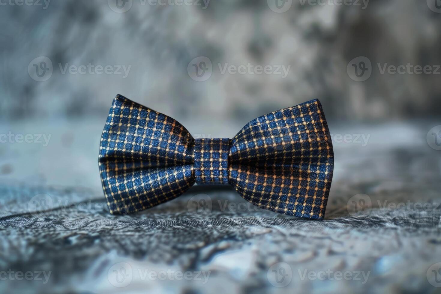 Blue bow tie with small golden squares pattern on a textured background photo