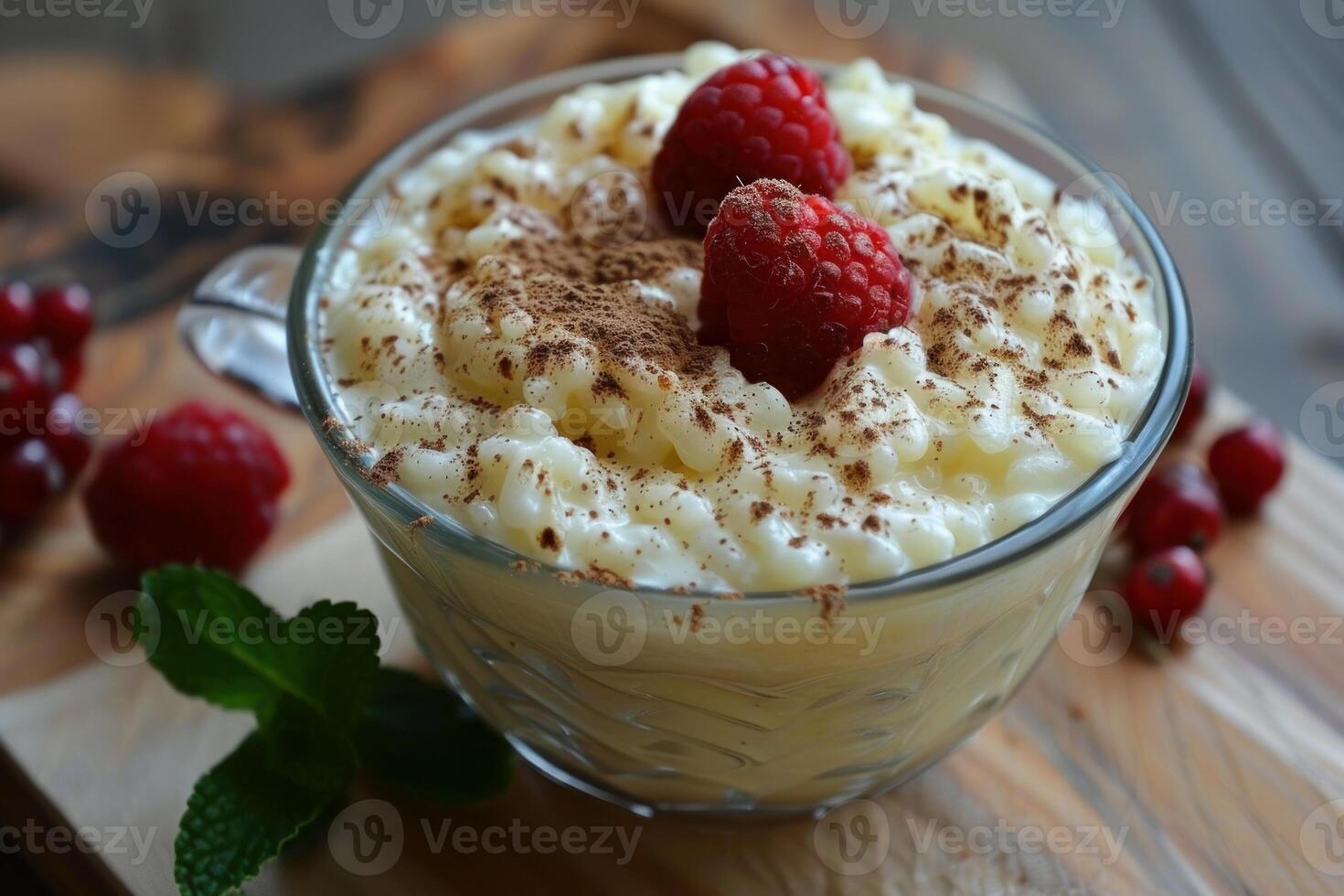 Creamy rice pudding decorated with raspberries and cinnamon in glass bowl photo