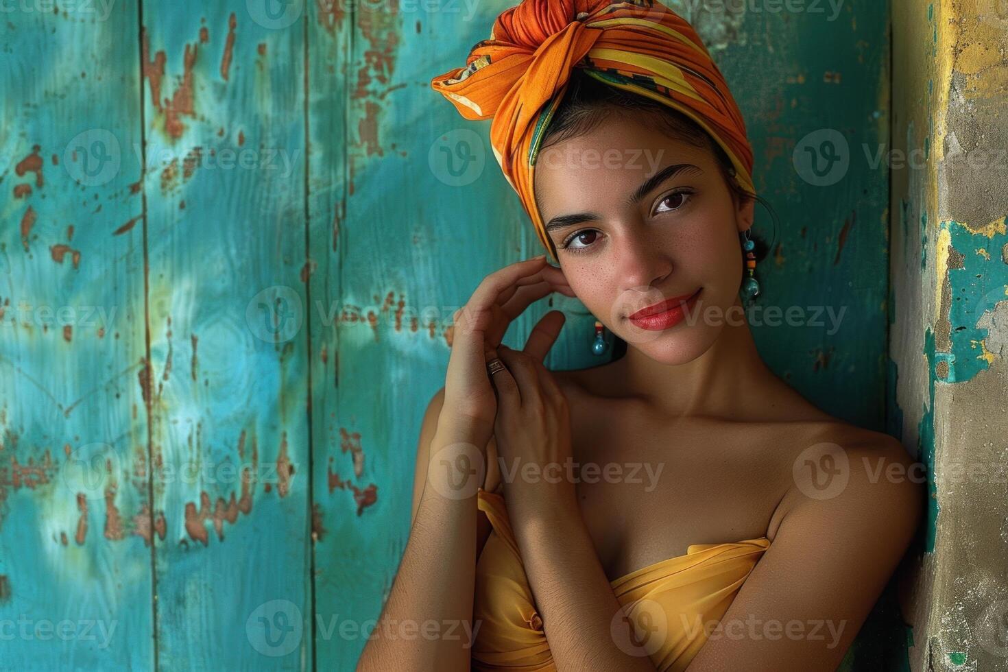 Latin woman wearing orange headscarf and yellow dress posing by turquoise door photo