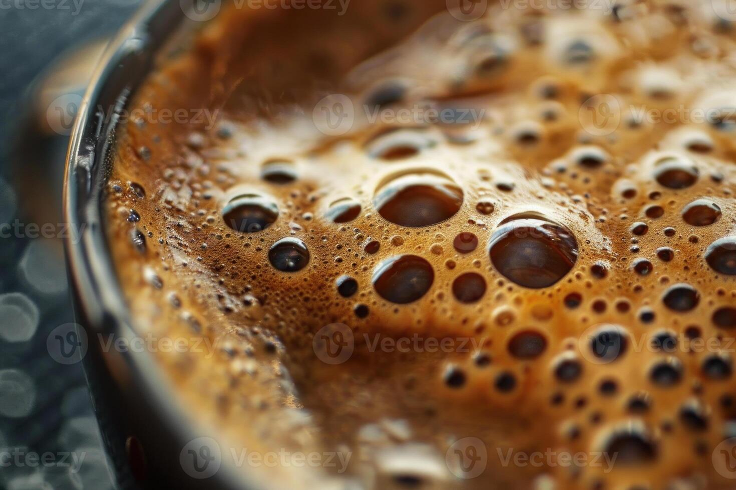 Close up of hot coffee foam creating bubbles in a dark mug photo