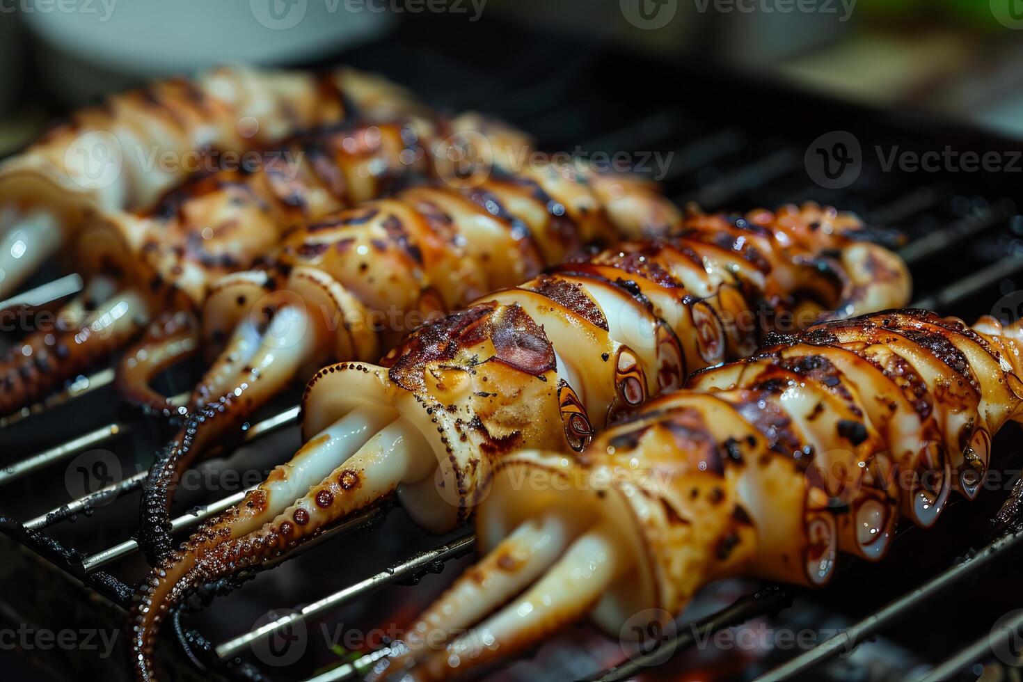 Grilled squids grilling on metal grill grates over coals in diagonal composition photo