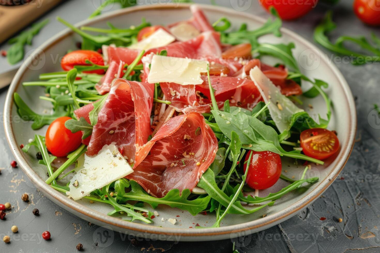 Delicious salad with arugula, coppa, tomatoes and parmesan cheese on gray background photo