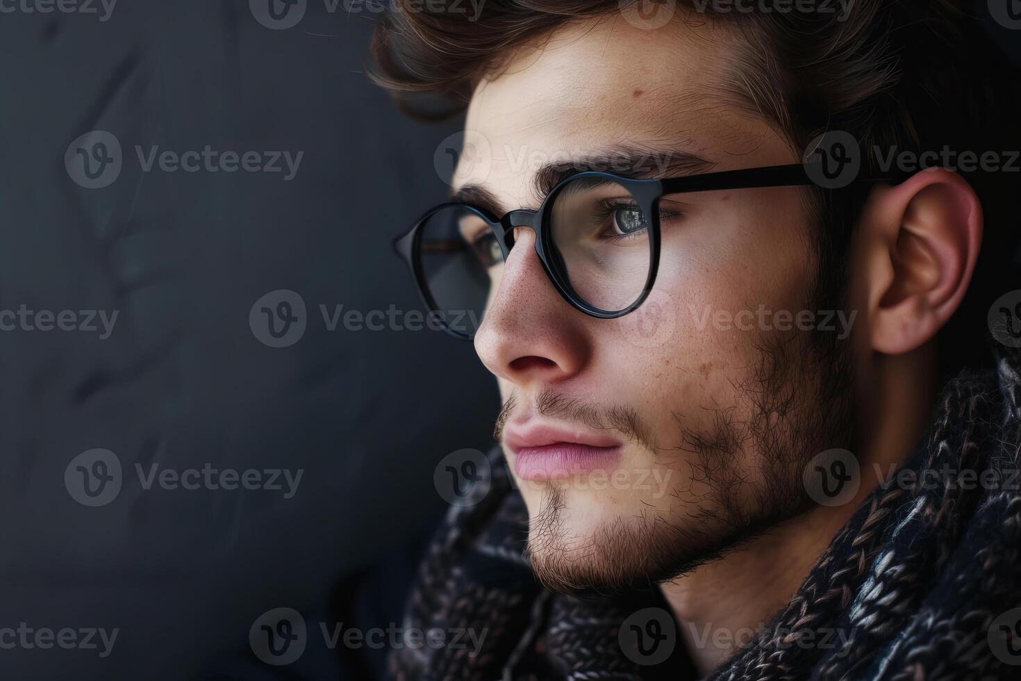 Pensive young man wearing glasses and scarf is thinking photo