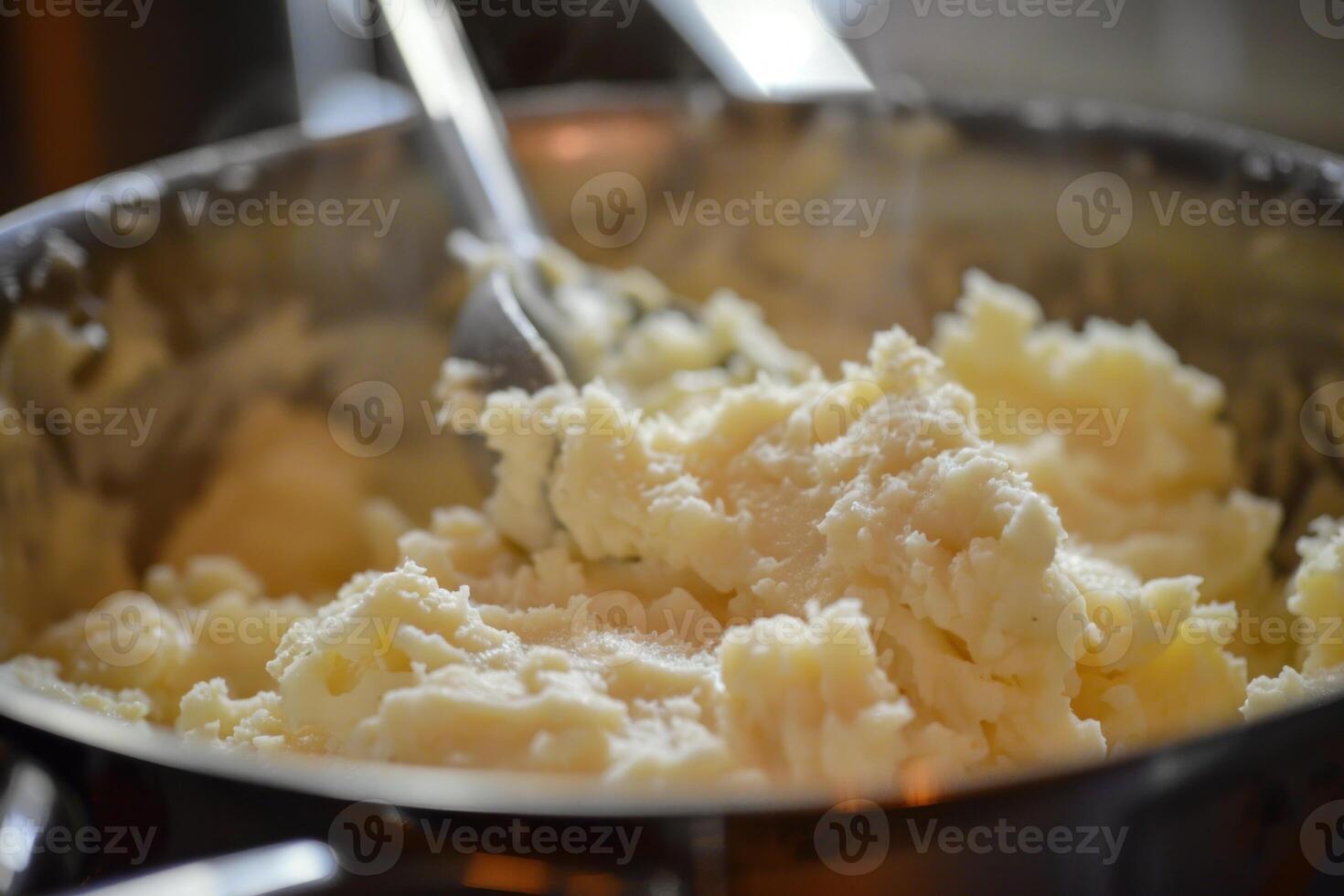 Chef mixing mashed potatoes in stainless steel pot with utensil photo