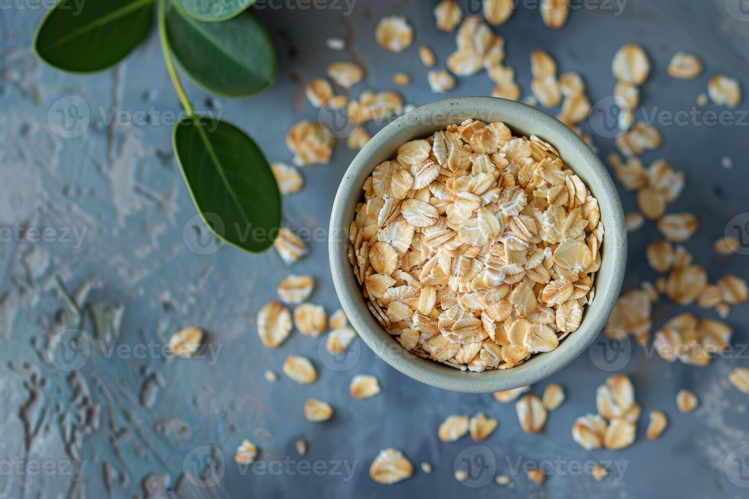 Rolled oats in a bowl with green leaves on rustic background photo