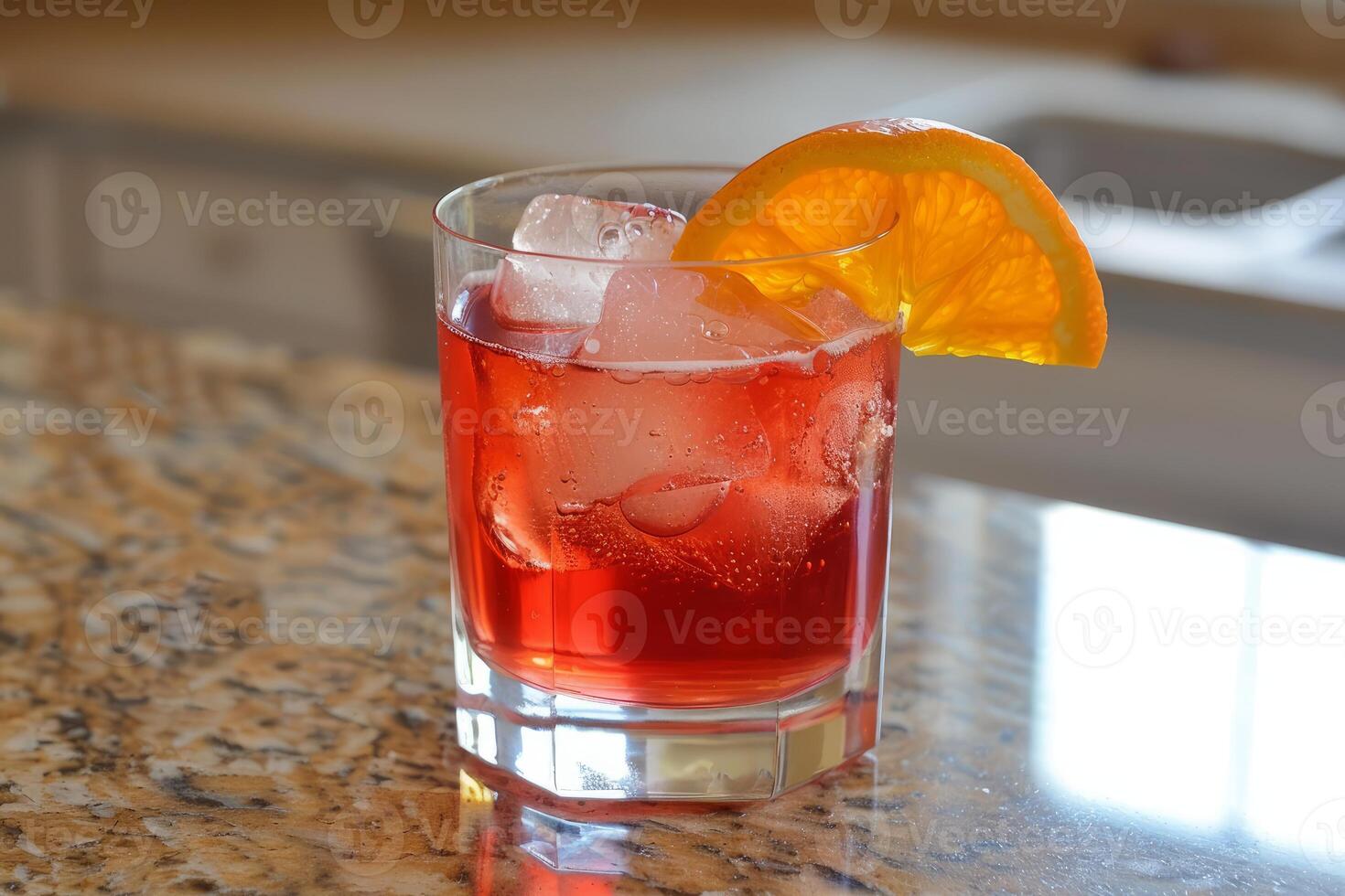 Refreshing red cocktail with ice cubes and orange slice on granite countertop photo