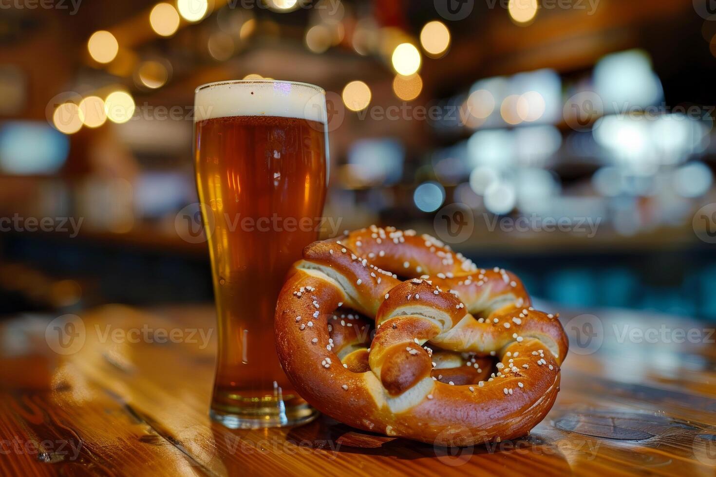 Glass of cold beer with soft pretzels resting on wooden table in blurred bar background photo