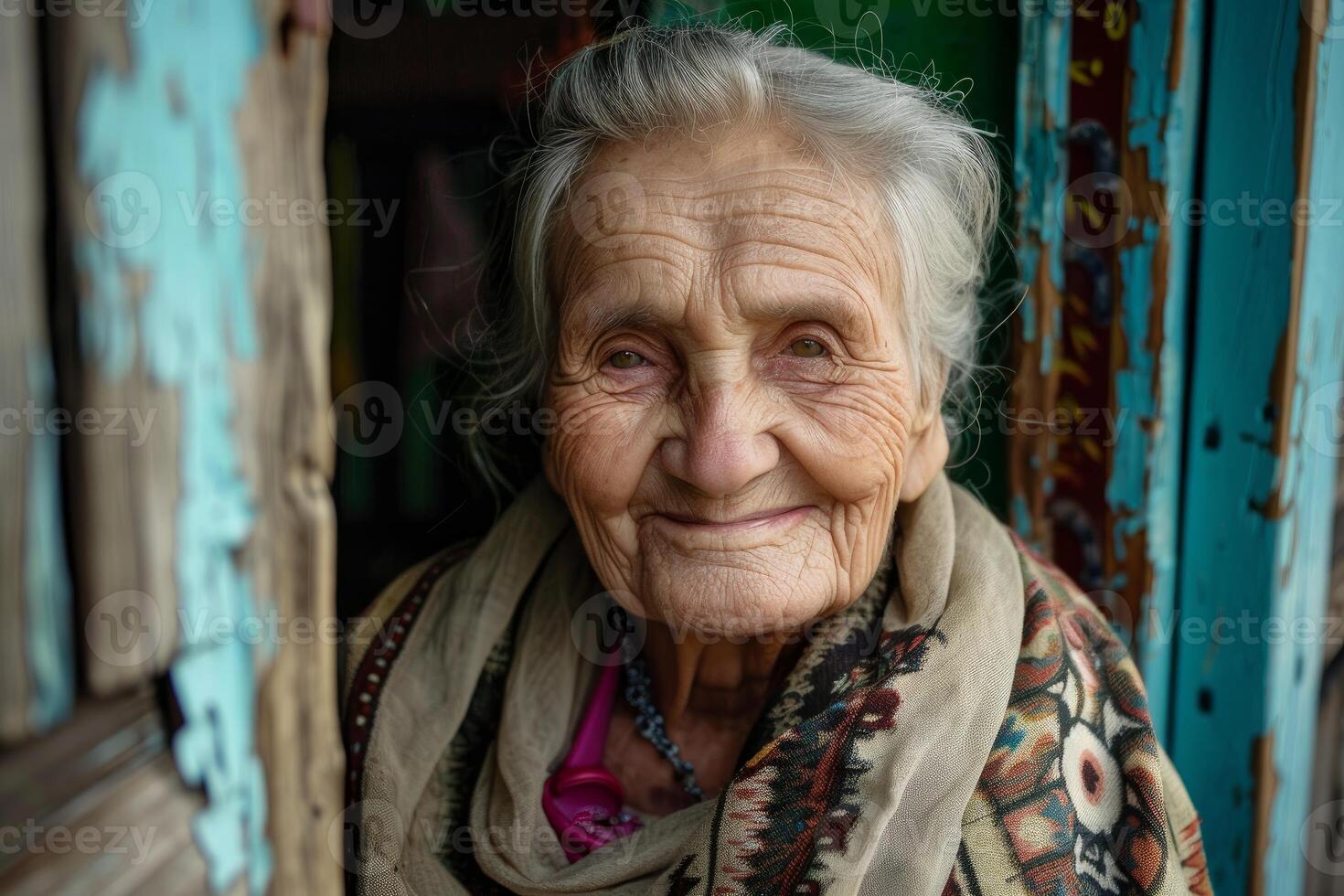 Portrait of smiling elderly woman with wrinkles wearing shawl by rustic door photo