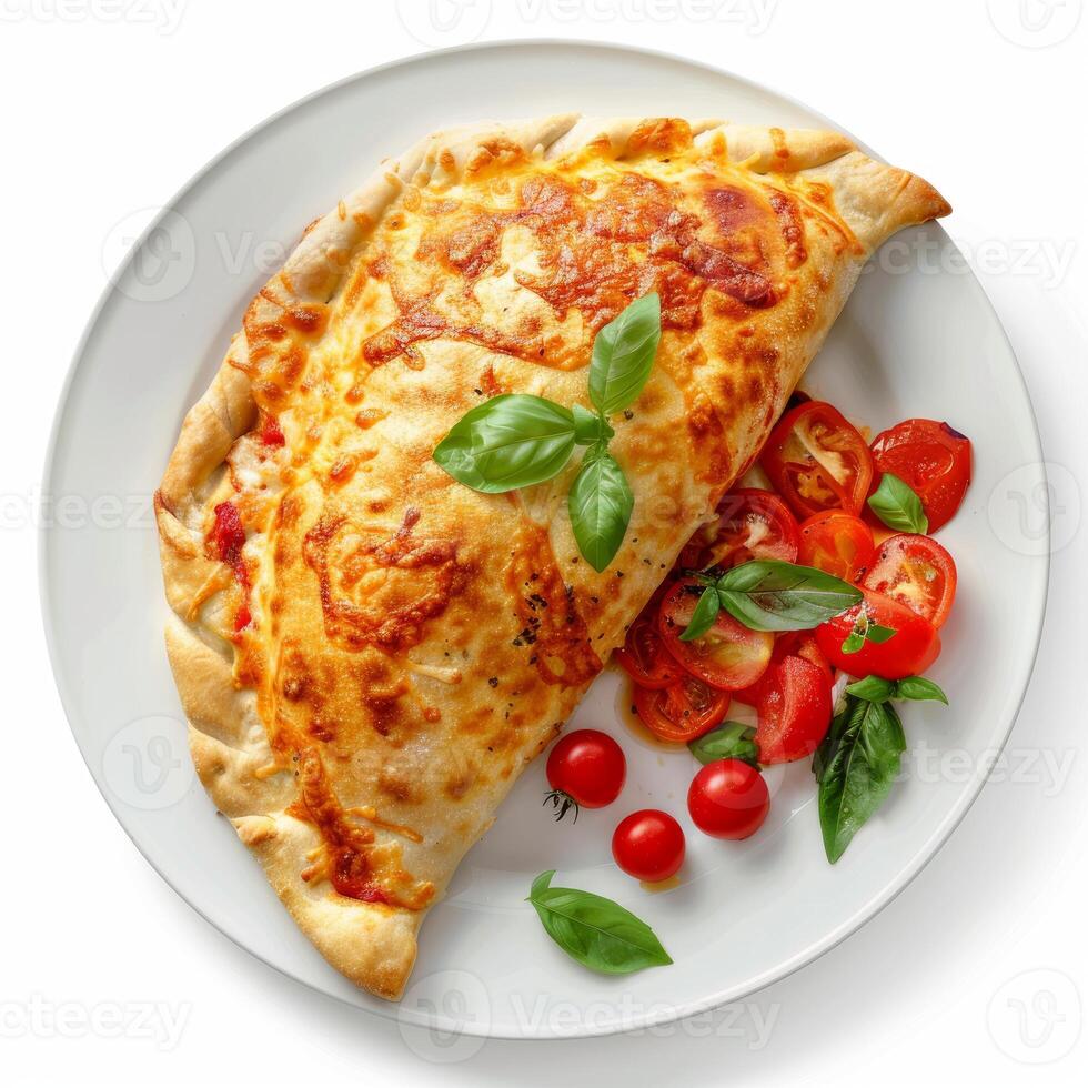 Delicious closed pizza calzone with tomato and basil on white plate photo