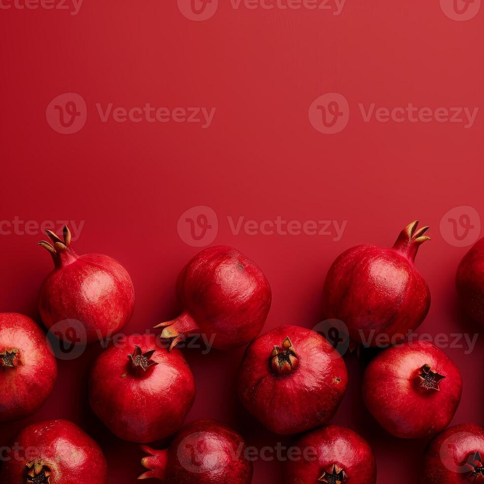 Ripe pomegranates creating a border on red background photo