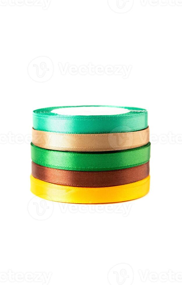 stack of satin ribbons in shades of yellow,brown, green against a white background photo