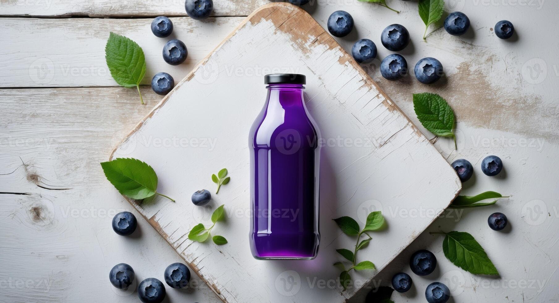 Vibrant violet blueberry juice bottle centered on white wooden board surrounded by fresh blueberries and green leaves viewed from above photo