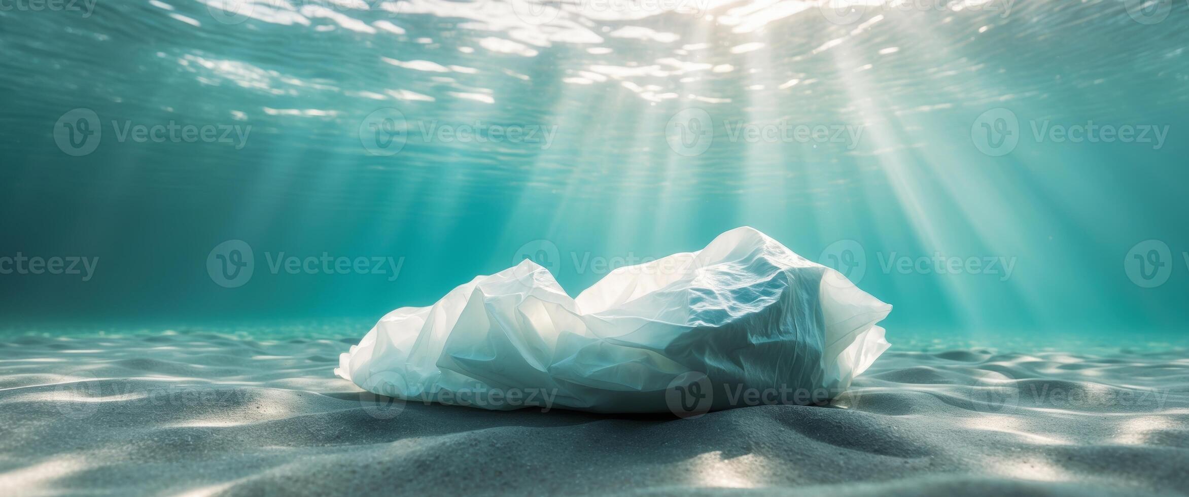 Crumpled plastic bag on the ocean floor with sunlight filtering through water. photo
