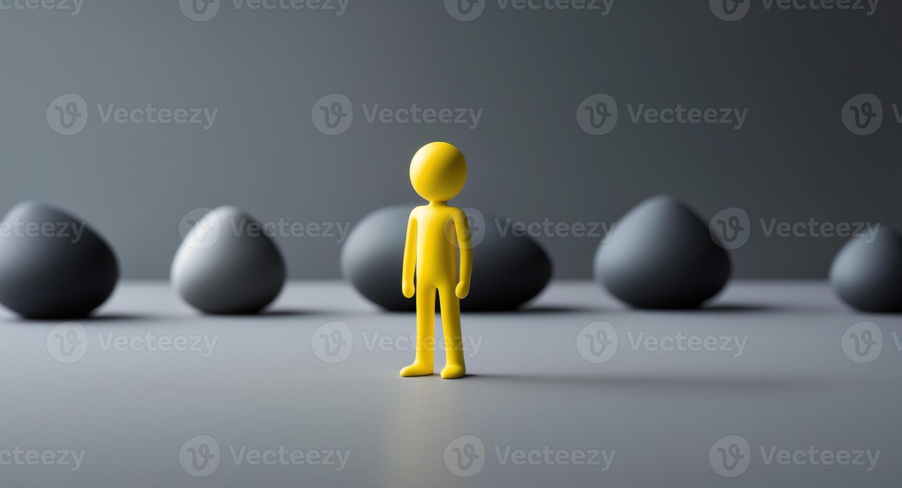 A solitary yellow figure stands illuminated amidst a group of dark rounded shapes photo