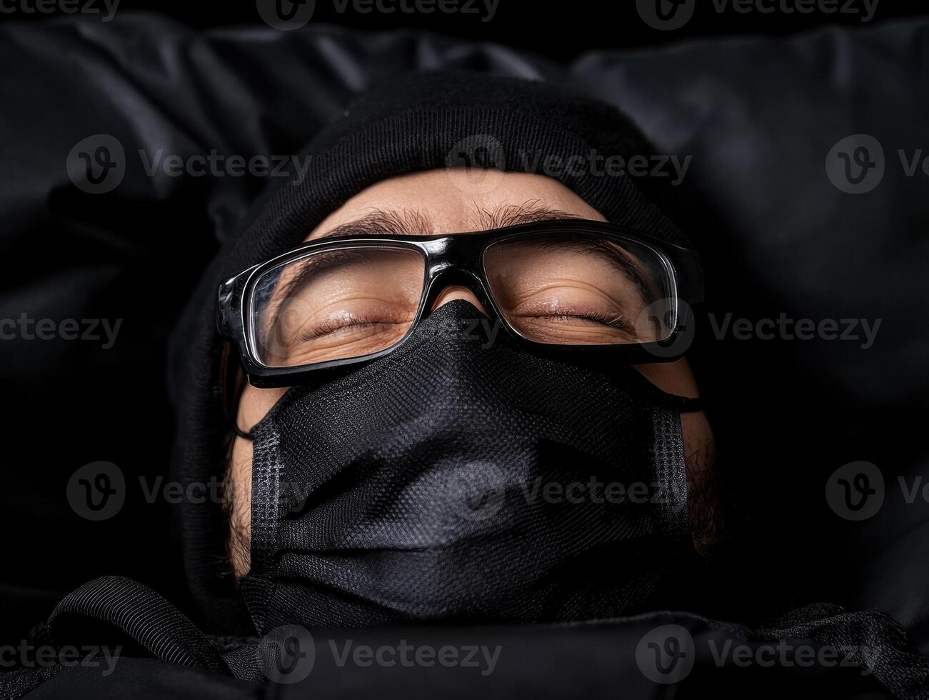 Close up of a person sleeping while wearing a black face mask and glasses photo