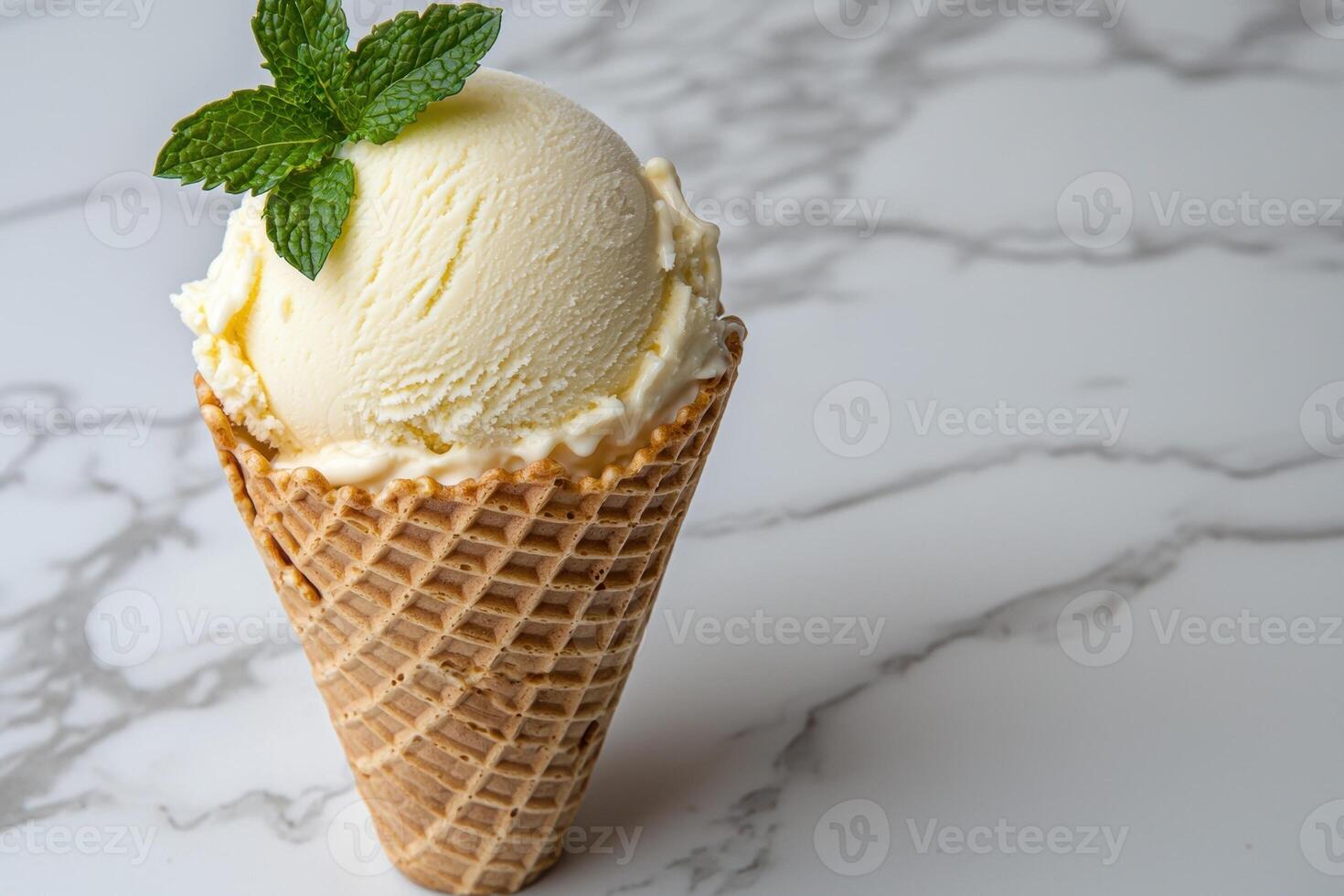 A scoop of vanilla ice cream in a waffle cone, garnished with mint photo