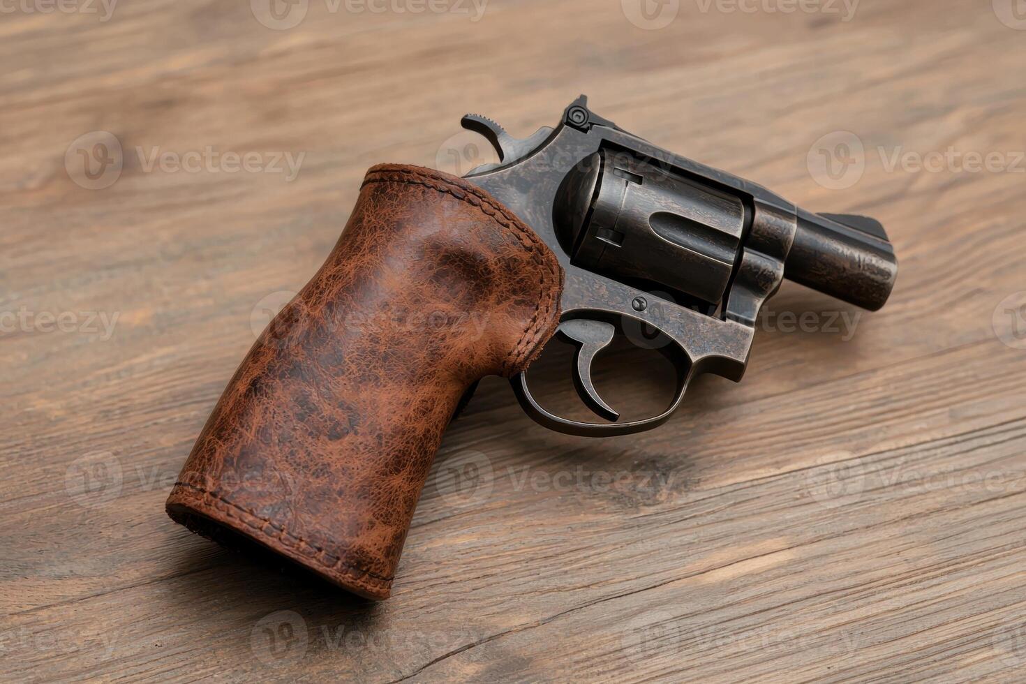 Close up of a revolver with a brown leather grip on a wooden surface photo