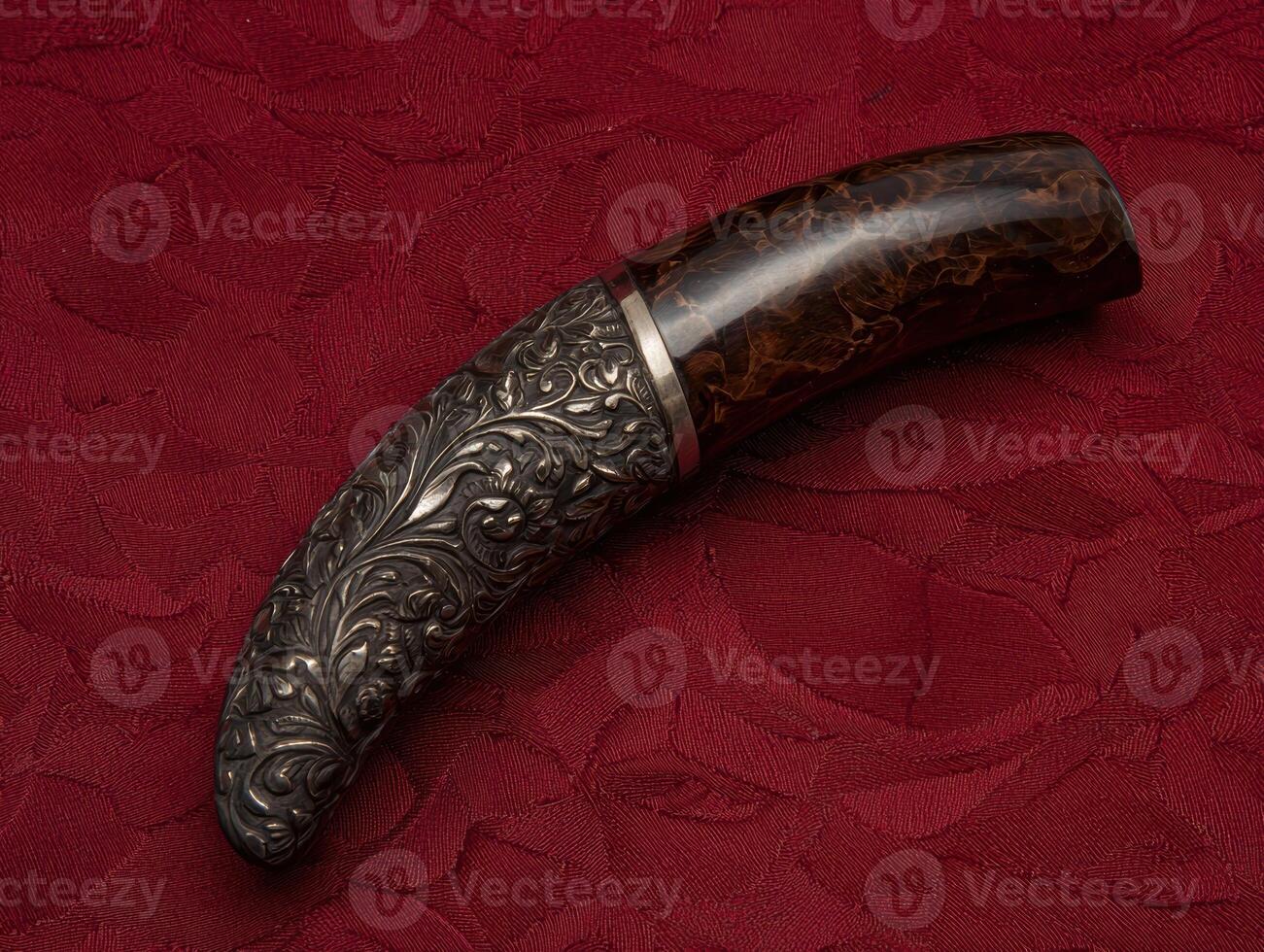 Ornate silver handle on a curved dark brown knife photo