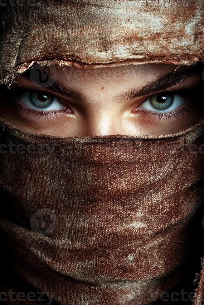 Mysterious woman with intense eyes peering from behind a brown cloth photo
