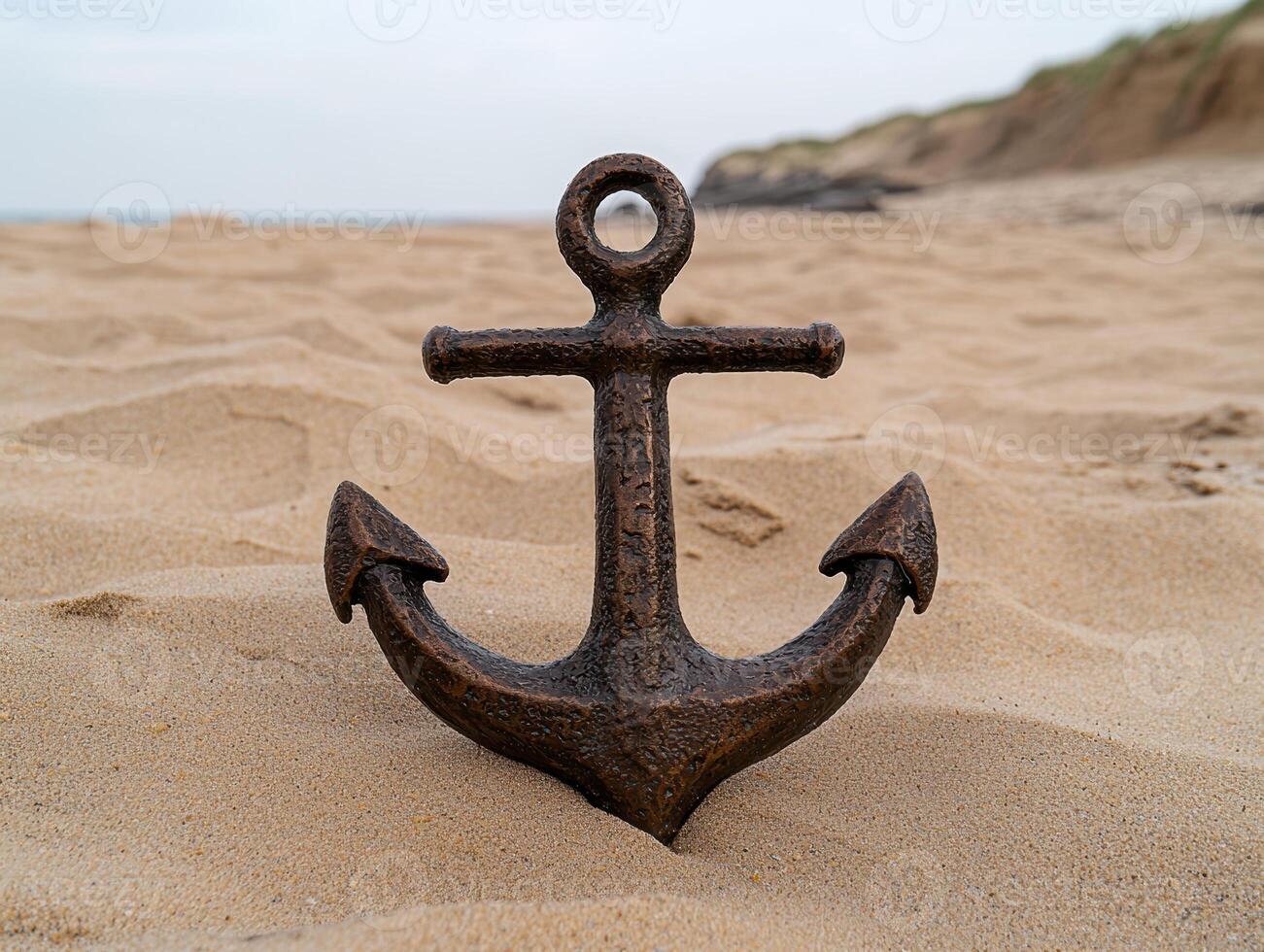 Bronze anchor on sandy beach, ocean background photo