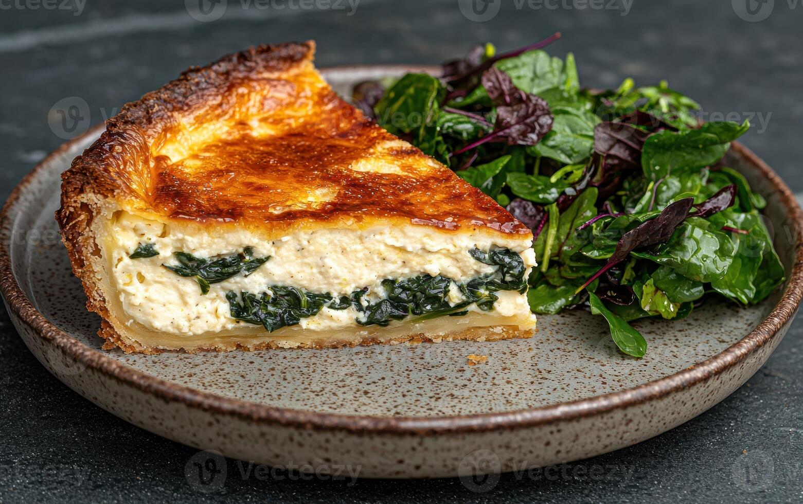 Slice of spinach and ricotta quiche with mixed greens salad photo